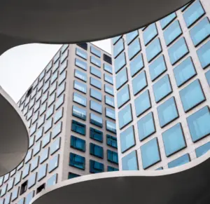 photo looking up through a curved window at a large building with many windows