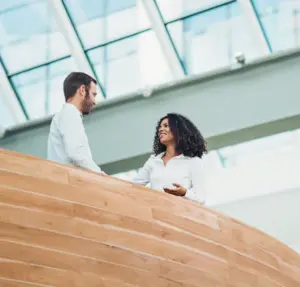 two people talking in a large open room with a glass ceiling