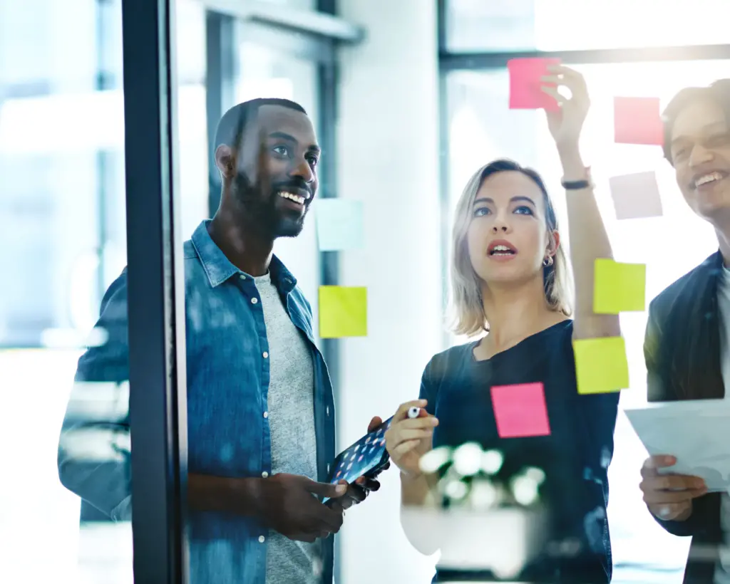 Three people placing sticky notes onto a window